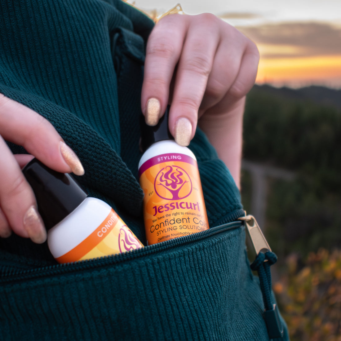 Person holding a bottle of Jessicurl hair product with a scenic background